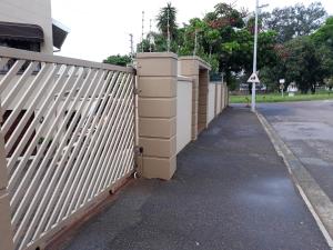 a white fence next to a street with a sidewalk at Joan's Bed and Breakfast in Durban