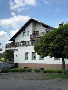 a white building with a balcony on top of it at Gästehaus Rehwinkel in Allenbach