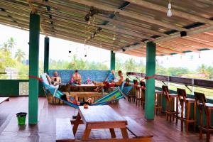 a group of people sitting in hammocks on a deck at Beach Break Surf Hostel in Weligama