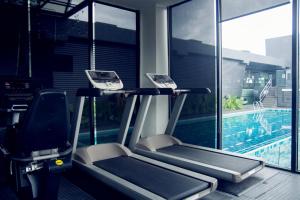 a gym with two tread machines next to a swimming pool at M Roof Hotel & Residences in Ipoh