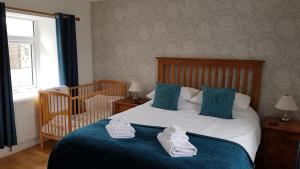 een slaapkamer met een wieg en een bed met handdoeken erop bij Cottages Lyndale Farm in Flashader