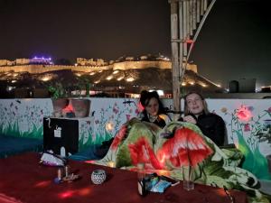two women sitting at a table at night with a castle in the background at Blue Eye Hostel in Jaisalmer