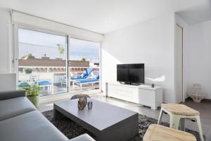 een woonkamer met een bank en een tv bij Sitges Group Blue&White in Sitges
