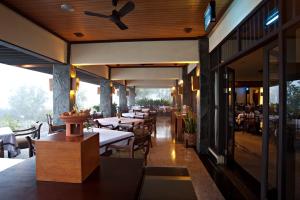 un restaurante con mesas y sillas y un ventilador de techo en Puteri Gunung Hotel, en Lembang