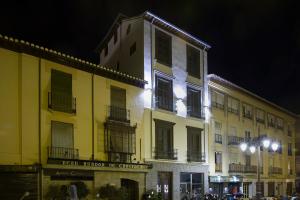 a large yellow building with windows and balconies at night at Imeda Apartamentos Escudo del Carmen 19 in Granada