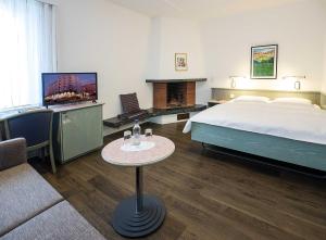 a hotel room with a bed and a tv and a table at Sommerau-Ticino Swiss Quality Hotel in Dietikon