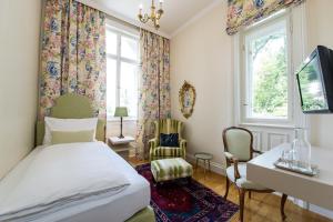 Un dormitorio con una cama y un escritorio y una ventana. en Dermuth Hotels – Parkvilla Wörth, en Pörtschach am Wörthersee