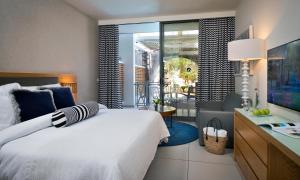 a bedroom with a white bed and a balcony at Agamim by Isrotel Collection in Eilat