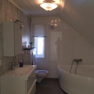 a bathroom with a sink and a tub and a toilet at Havbris in Bremnes