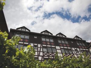 a black and white building with trees in the foreground at Hotel Felsenkeller in Rüdesheim am Rhein