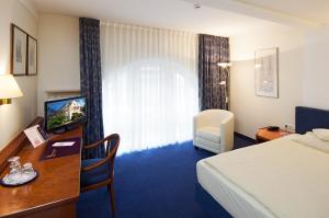 ケルンにあるホテル ヴィクトリアのベッド、デスク、テレビが備わるホテルルームです。