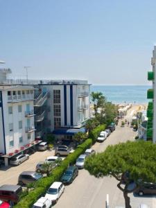a street with cars parked in a parking lot next to the beach at Hotel Palme in Lido di Jesolo