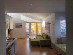 ein Wohnzimmer mit einem grünen Sofa und einer Küche in der Unterkunft Ferienwohnung Schweiberer in Fügen