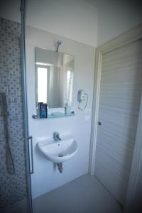 a white bathroom with a sink and a mirror at Hotel Jesolo Sand in Lido di Jesolo