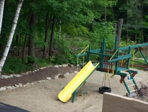 a playground with a yellow slide in a park at Tall Pines Motel in Lake George