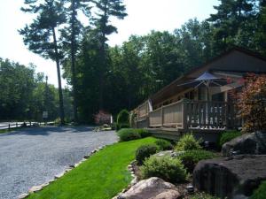 a house with a porch with an umbrella on a driveway at Tall Pines Motel in Lake George