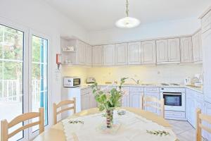a kitchen with white cabinets and a table and chairs at Beach Villa Oneiro in Apraos