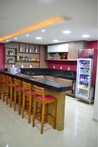 a kitchen with a bar with wooden chairs and a refrigerator at Evidence Hotel in Sapucaia