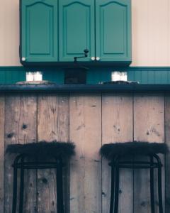a kitchen counter with green cabinets and two black bar stools at The Mangevie in Furudal +132 photos
