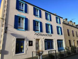 un bâtiment blanc avec volets bleus dans une rue dans l'établissement L'Hôtel de Loctudy, à Loctudy