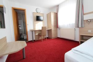 a room with a red carpet and a table and a desk at Hotel Schoch, Trossingen in Trossingen