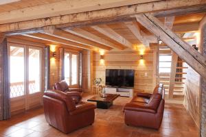 a living room with leather chairs and a flat screen tv at Le Refuge in Cordon