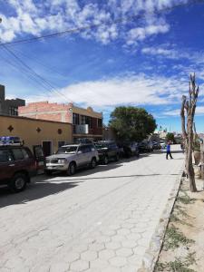 a person walking down a street with cars parked at Hotel Aguilar in Uyuni