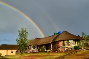 a rainbow in the sky over a house at Ribaneng Lodge in Ribaneng