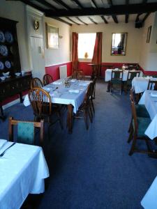 uma sala de jantar com mesas e cadeiras com toalhas de mesa brancas em The Royal Oak em Kington