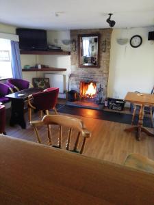 ein Wohnzimmer mit einem Kamin, Stühlen und einem Tisch in der Unterkunft The Royal Oak in Kington