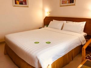 فندق المدينة هوليداي في مسقط: غرفة نوم بسرير ابيض وعليه وجه