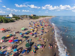a crowd of people on a beach with umbrellas at Condominio del Faro - Quequen in Necochea