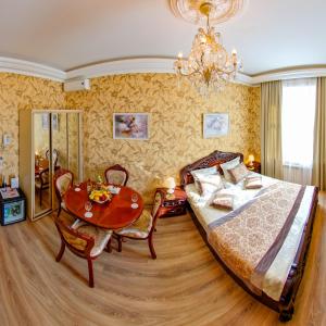 een slaapkamer met een bed, een tafel en een kroonluchter bij Hotel Golden Palace in Sint-Petersburg