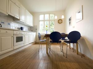 a kitchen with white cabinets and a table and chairs at Auf dem Berg Hude in Hude