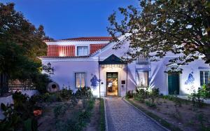 a white house with a pathway leading to the front door at Turim Club D'Azeitao Hotel in Setúbal