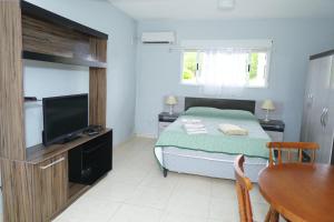 a bedroom with a bed and a tv and a table at Palmas del Caribe in Punta Del Diablo