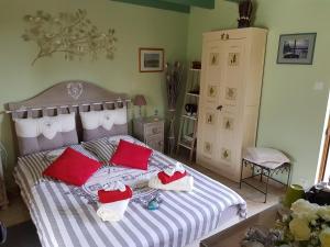 a bedroom with a bed with red and white pillows at Le Chat Courant in Villandry
