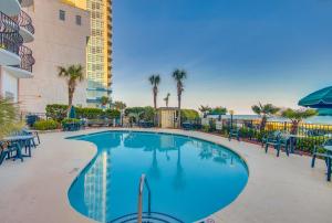a swimming pool at a resort with chairs and palm trees at Beachfront Luxury Condo w Private Balcony in Myrtle Beach