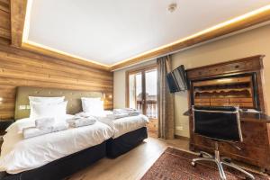 a bedroom with a bed and a desk and a television at Chamois d'Or Hotel in Les Gets