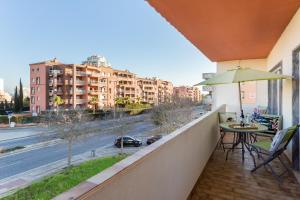 einen Balkon mit einem Tisch, einem Sonnenschirm und einer Straße in der Unterkunft Edifício Rocha Vau Beach Apartment in Portimão