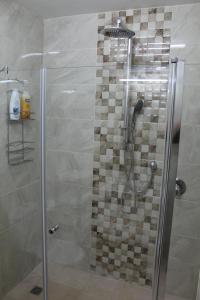 een douche in een badkamer met een glazen deur bij Villa Kibel Apartments in Eilat