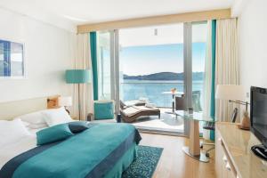 een slaapkamer met een bed en uitzicht op de oceaan bij Sun Gardens Dubrovnik in Dubrovnik