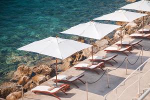 a group of chairs and umbrellas on the beach at Sun Gardens Dubrovnik in Dubrovnik