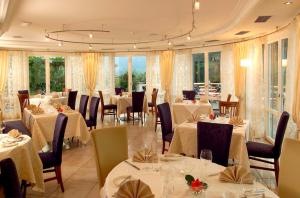 un restaurante con mesas y sillas blancas y ventanas en Hotel Hanny, en Bolzano
