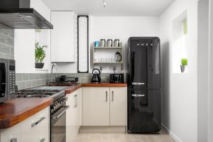 a kitchen with white cabinets and a black refrigerator at The Coach House Montpellier in Cheltenham