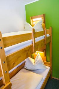 Ce lit se trouve dans un dortoir doté de 2 lits superposés et d'un mur vert. dans l'établissement Jugendherberge Füssen, à Füssen