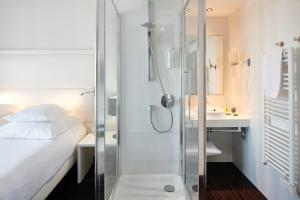 a bathroom with a shower and a bed and a sink at Hôtel Le Windsor Biarritz in Biarritz
