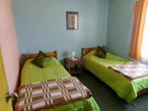 1 dormitorio con 2 camas, mesa y ventana en Hotel Ventura, en Chile Chico