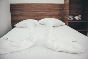 dos toallas con forma de cisnes sentados en una cama en Souza Reis Flat, en São Thomé das Letras