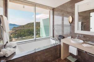 a bathroom with a tub and a sink and a window at Sun Gardens Dubrovnik in Dubrovnik